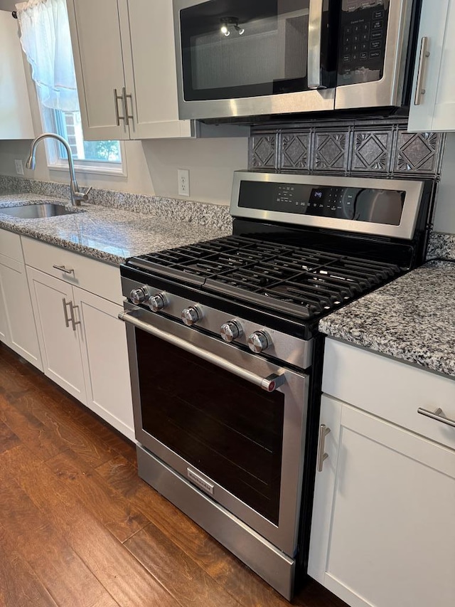 8298 Southfork Rd, Baxter, TN 38544 - kitchen featuring appliances with stainless steel finishes, light stone countertops, dark wood finished floors, and white cabinets