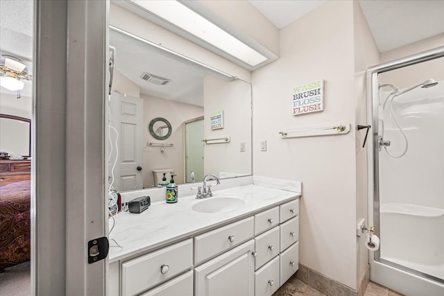 bathroom with vanity, a shower stall, visible vents, and baseboards