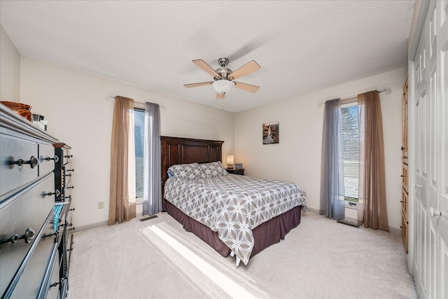 bedroom featuring a ceiling fan, light colored carpet, a textured ceiling, and baseboards