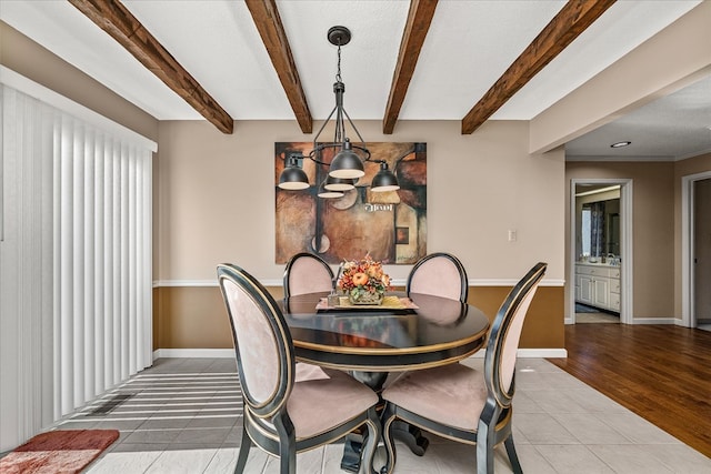 dining area featuring tile patterned flooring, beamed ceiling, a textured ceiling, and baseboards