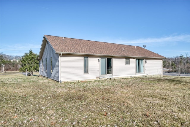 back of house with a shingled roof and a lawn