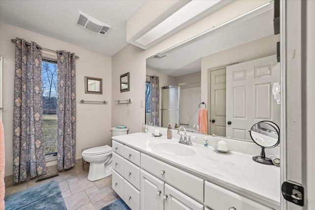 bathroom featuring stone tile floors, visible vents, toilet, vanity, and a textured ceiling