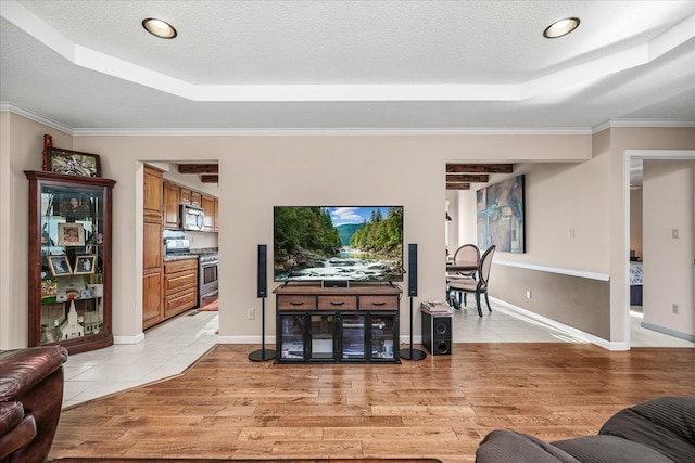 living area featuring light wood-style flooring, a tray ceiling, and a textured ceiling