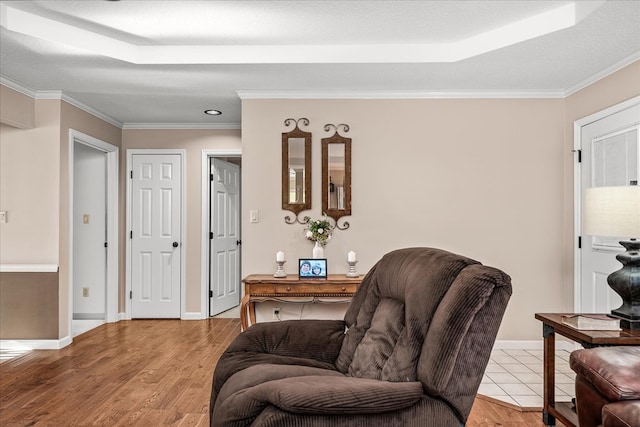 living area featuring a textured ceiling, ornamental molding, and light wood-style floors