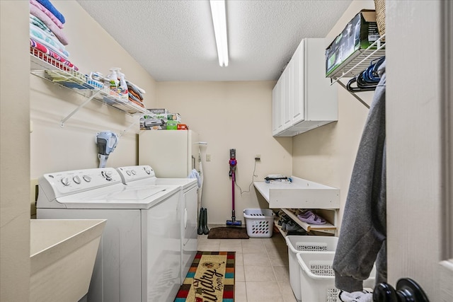 clothes washing area featuring cabinet space, light tile patterned flooring, a sink, a textured ceiling, and washer and dryer