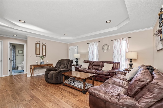 living area featuring a textured ceiling, a tray ceiling, wood finished floors, and ornamental molding