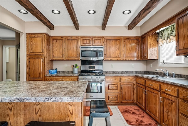 kitchen featuring a kitchen bar, appliances with stainless steel finishes, brown cabinets, and a sink