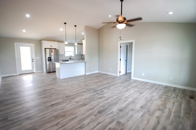 interior space featuring open floor plan, stainless steel fridge with ice dispenser, decorative light fixtures, and white cabinets