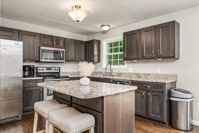 139 Rachelle Pl, Baxter, TN 38544 - kitchen with appliances with stainless steel finishes, dark brown cabinetry, a kitchen bar, a center island, and dark wood-style floors