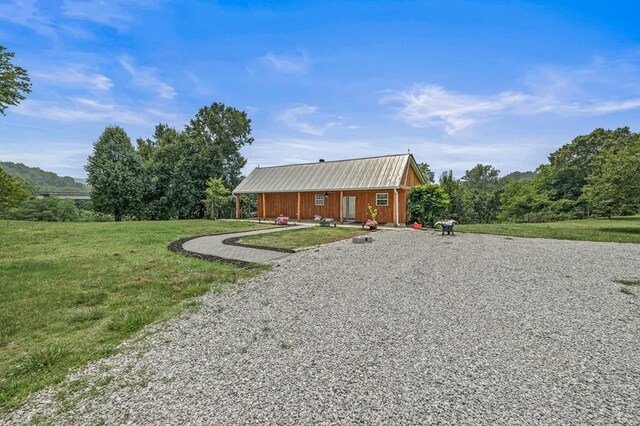 view of front of property featuring driveway, metal roof, and a front yard