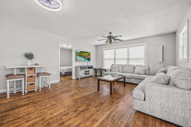 living area with a healthy amount of sunlight, baseboards, a ceiling fan, and dark wood-type flooring