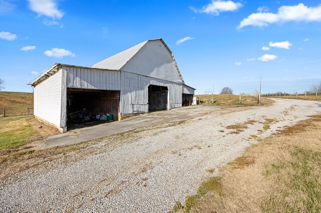 view of barn with driveway and a rural view