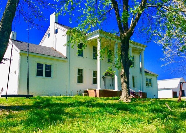 back of property featuring a yard, a chimney, and stucco siding