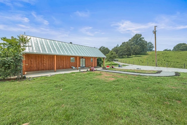 exterior space featuring a front yard, a rural view, and metal roof