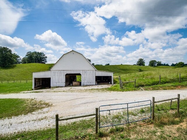 view of outbuilding with an outbuilding, a rural view, and fence