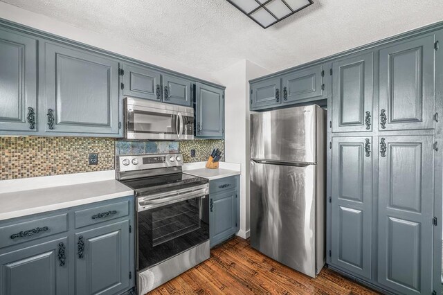 kitchen featuring tasteful backsplash, appliances with stainless steel finishes, dark wood-style flooring, light countertops, and a textured ceiling