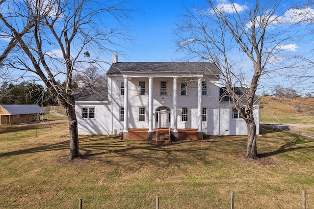 neoclassical home featuring a chimney and a front lawn