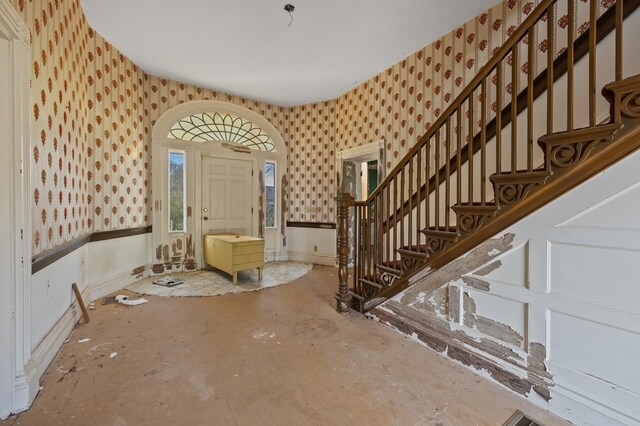 entrance foyer featuring wallpapered walls, baseboards, and stairway