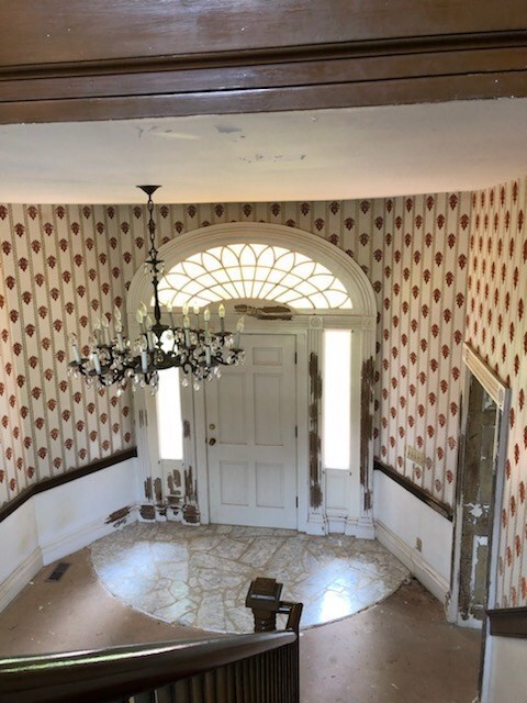 foyer featuring baseboards, an inviting chandelier, and wallpapered walls