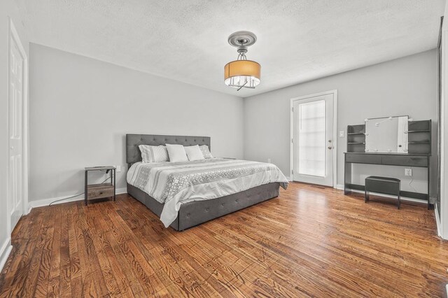 bedroom with dark wood-style floors, a textured ceiling, and baseboards