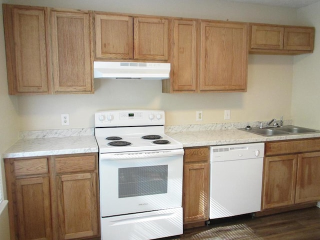 kitchen featuring under cabinet range hood, white appliances, a sink, light countertops, and dark wood-type flooring