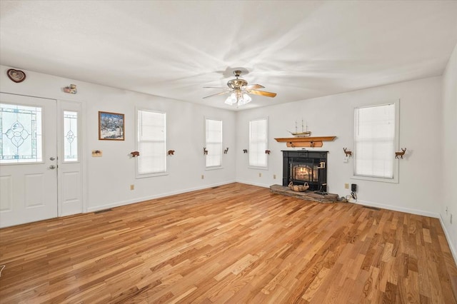 unfurnished living room featuring a wealth of natural light, light wood-type flooring, and baseboards