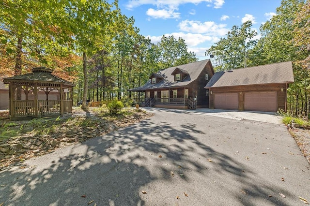 rustic home with a porch, an attached garage, driveway, and a gazebo