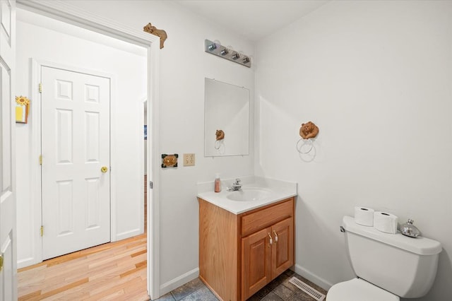 bathroom featuring toilet, wood finished floors, vanity, and baseboards