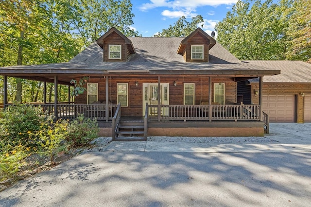 rustic home with a garage, a shingled roof, and a porch