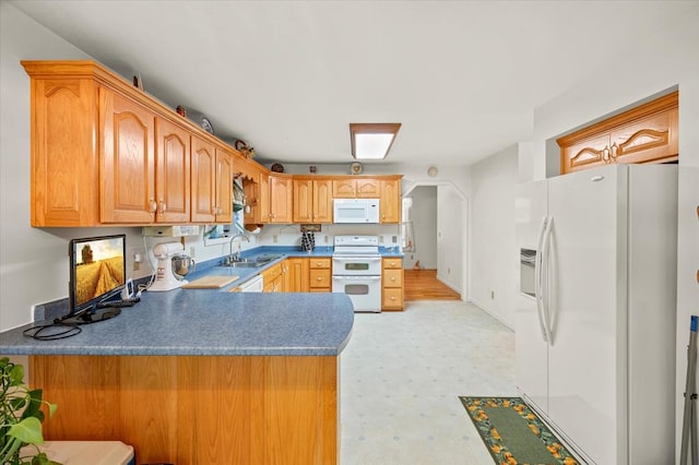 kitchen with white appliances, a peninsula, light countertops, light floors, and a sink