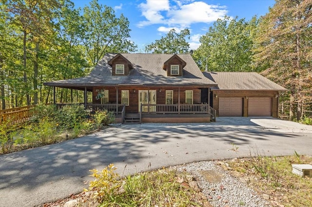 chalet / cabin with a porch, driveway, and an attached garage