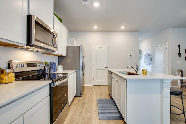 222 Dale Mires Ln, Baxter, TN 38544 - kitchen featuring appliances with stainless steel finishes, a center island with sink, light wood-style floors, a kitchen breakfast bar, and white cabinets