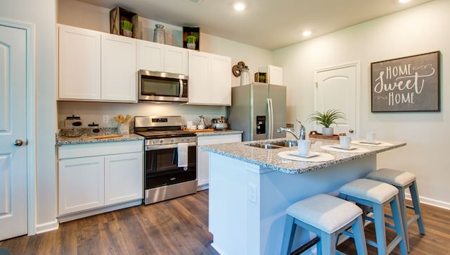 222 Dale Mires Ln, Baxter, TN 38544 - kitchen with stainless steel appliances, dark wood-style floors, a kitchen island with sink, a kitchen breakfast bar, and light stone countertops