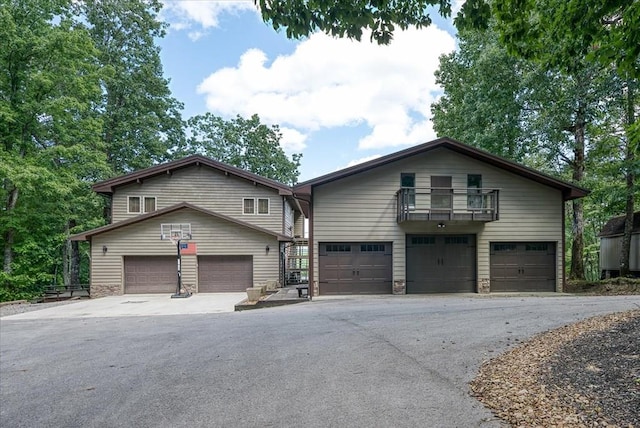 view of front of house with stone siding, aphalt driveway, and a balcony