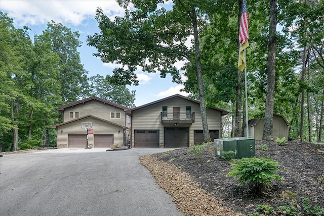 view of front of home with aphalt driveway, a balcony, and a storage shed