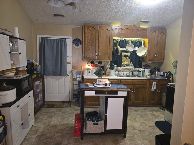 3073 Fisk Rd, Cookeville, TN 38506 - kitchen featuring black microwave, brown cabinetry, range, a textured ceiling, and a center island