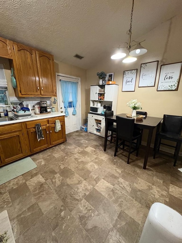 3073 Fisk Rd, Cookeville, TN 38506 - kitchen featuring brown cabinetry, light countertops, a chandelier, hanging light fixtures, and stone finish floors