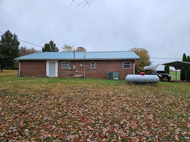 rear view of house featuring metal roof, central AC, and brick siding