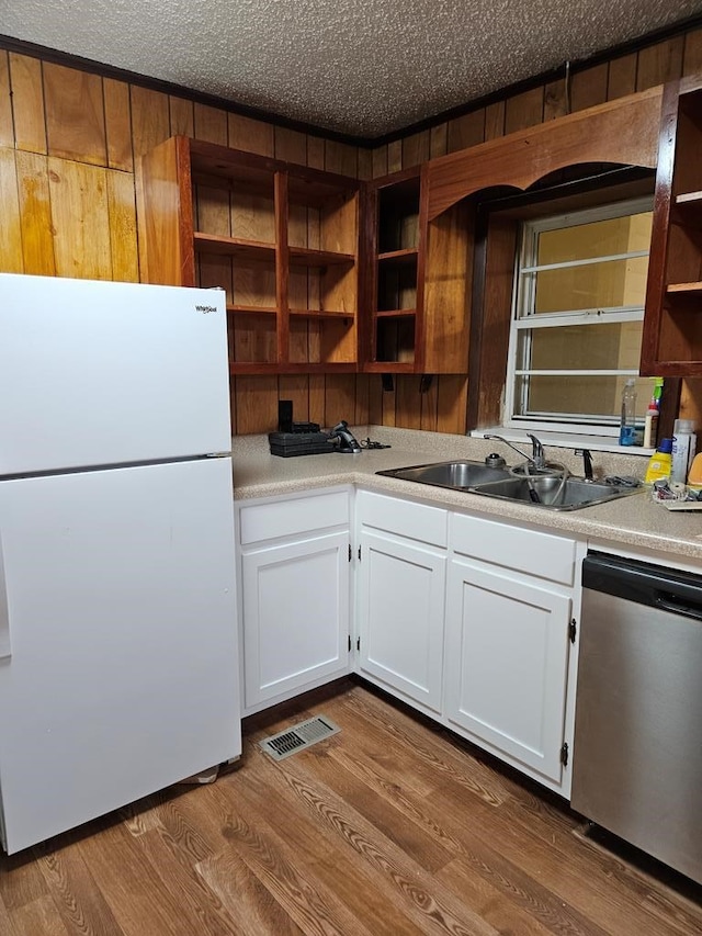 kitchen with a sink, white cabinets, stainless steel dishwasher, and freestanding refrigerator