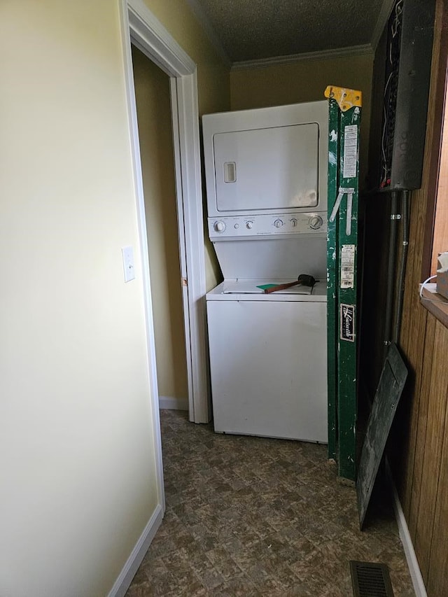 washroom featuring laundry area, visible vents, baseboards, stacked washing maching and dryer, and crown molding