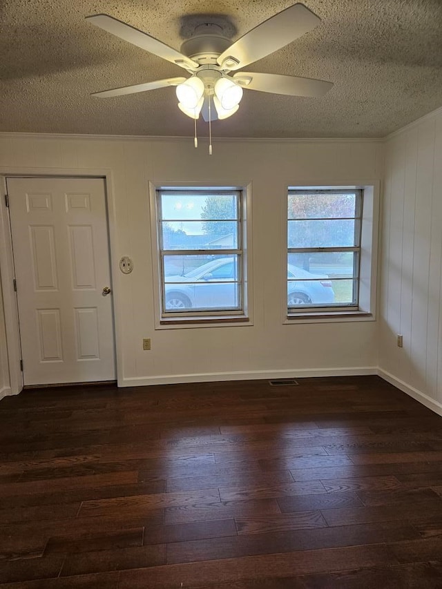 spare room featuring plenty of natural light, a ceiling fan, dark wood finished floors, and a textured ceiling