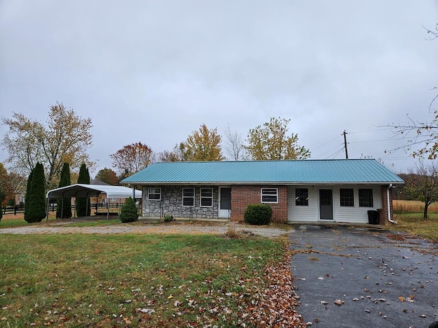 ranch-style home with metal roof, stone siding, a detached carport, and a front yard