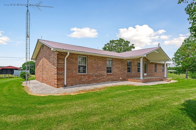 rear view of property with a yard, brick siding, and metal roof