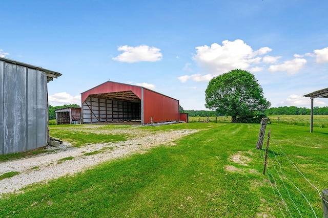 view of yard with a pole building, an outdoor structure, driveway, and a detached garage