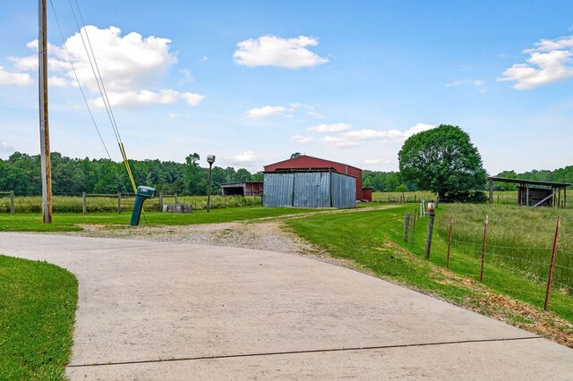 view of road with driveway, a pole building, and a rural view