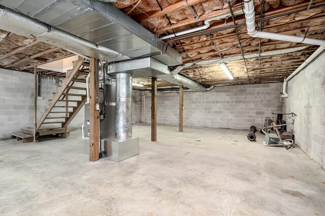 unfinished basement with heating unit and stairs