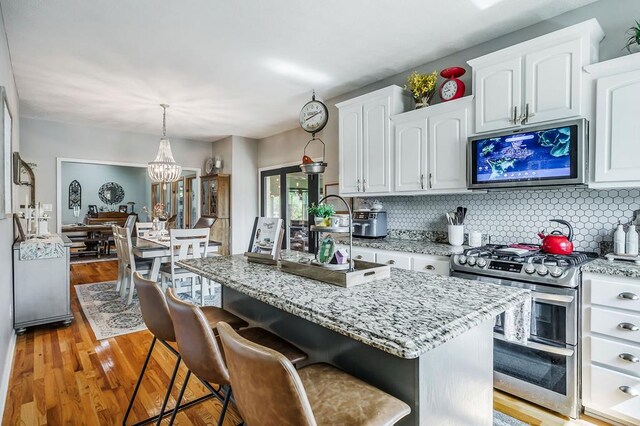 kitchen featuring white cabinetry, a kitchen island, appliances with stainless steel finishes, and decorative light fixtures