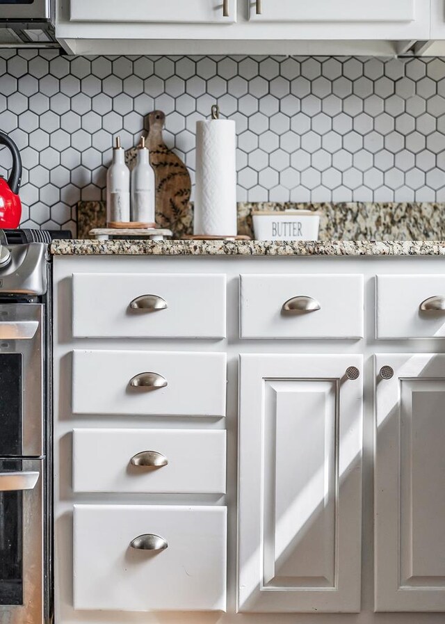 details with tasteful backsplash, white cabinetry, and light countertops