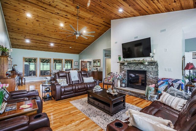 living area featuring light wood finished floors, wood ceiling, ceiling fan, a fireplace, and high vaulted ceiling