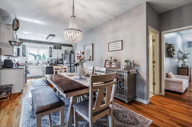 dining area featuring a notable chandelier, baseboards, and wood finished floors